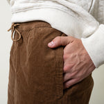 Brown corduroy pants with a white sweater and beige background