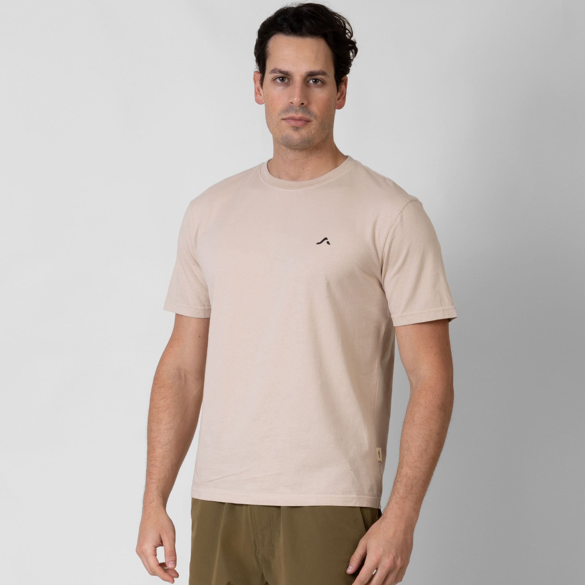 Man wearing a beige t-shirt with a small black onda logo on a white background