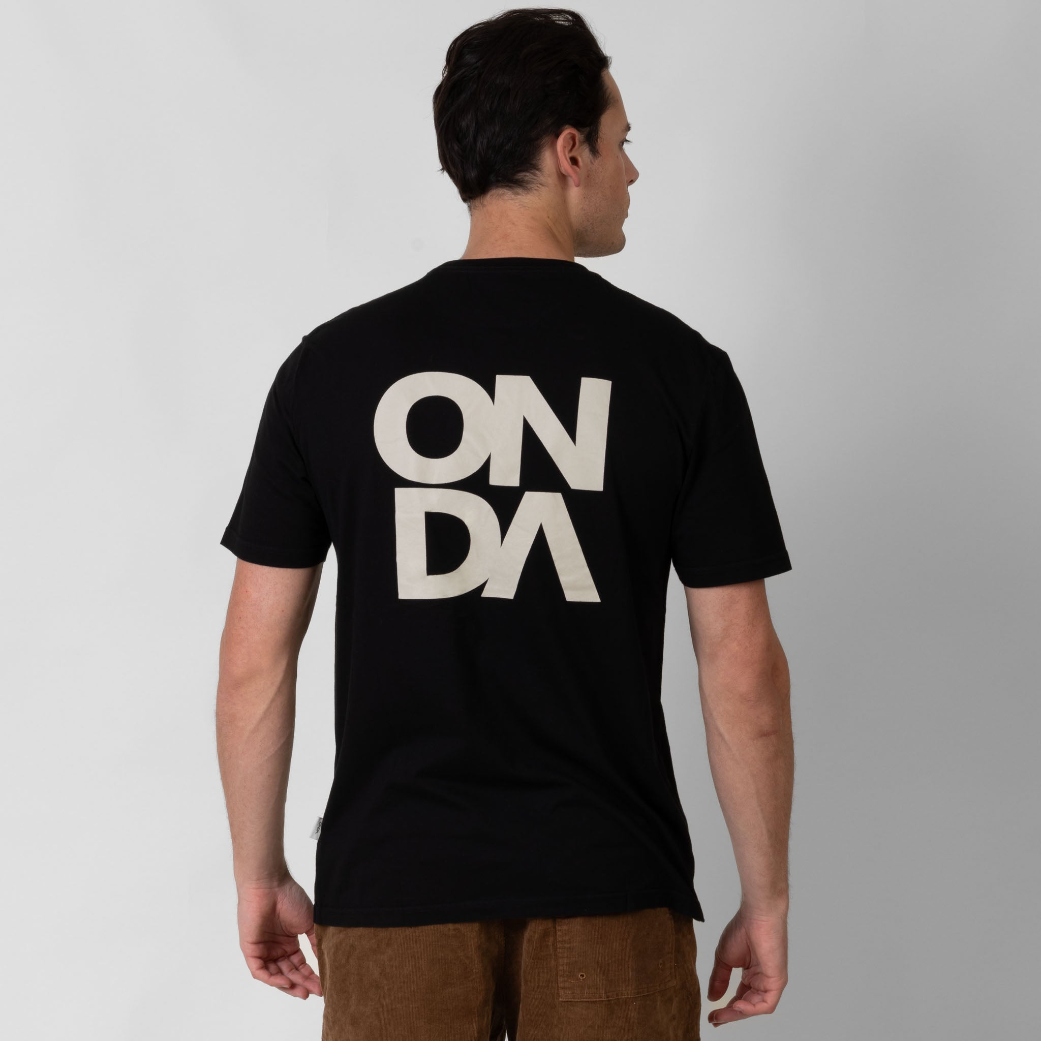 Man wearing a black t-shirt with white 'ONDA' logo on the back against a white background
