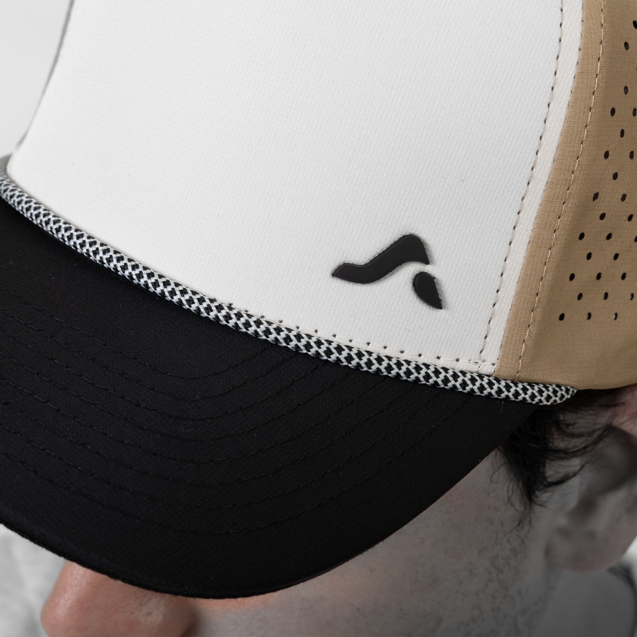Close-up of a cap with a black onda logo on a neutral background