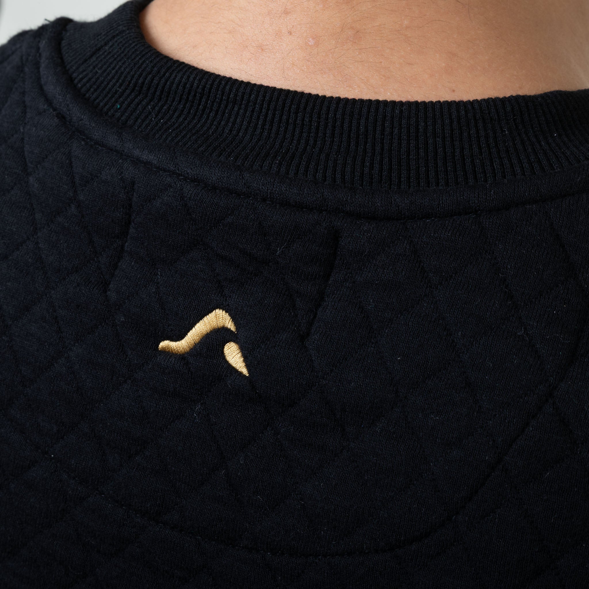 Black textured garment with a small embroidered onda logo on a plain background