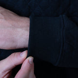 Close-up of a person adjusting the sleeve of a dark sweater.