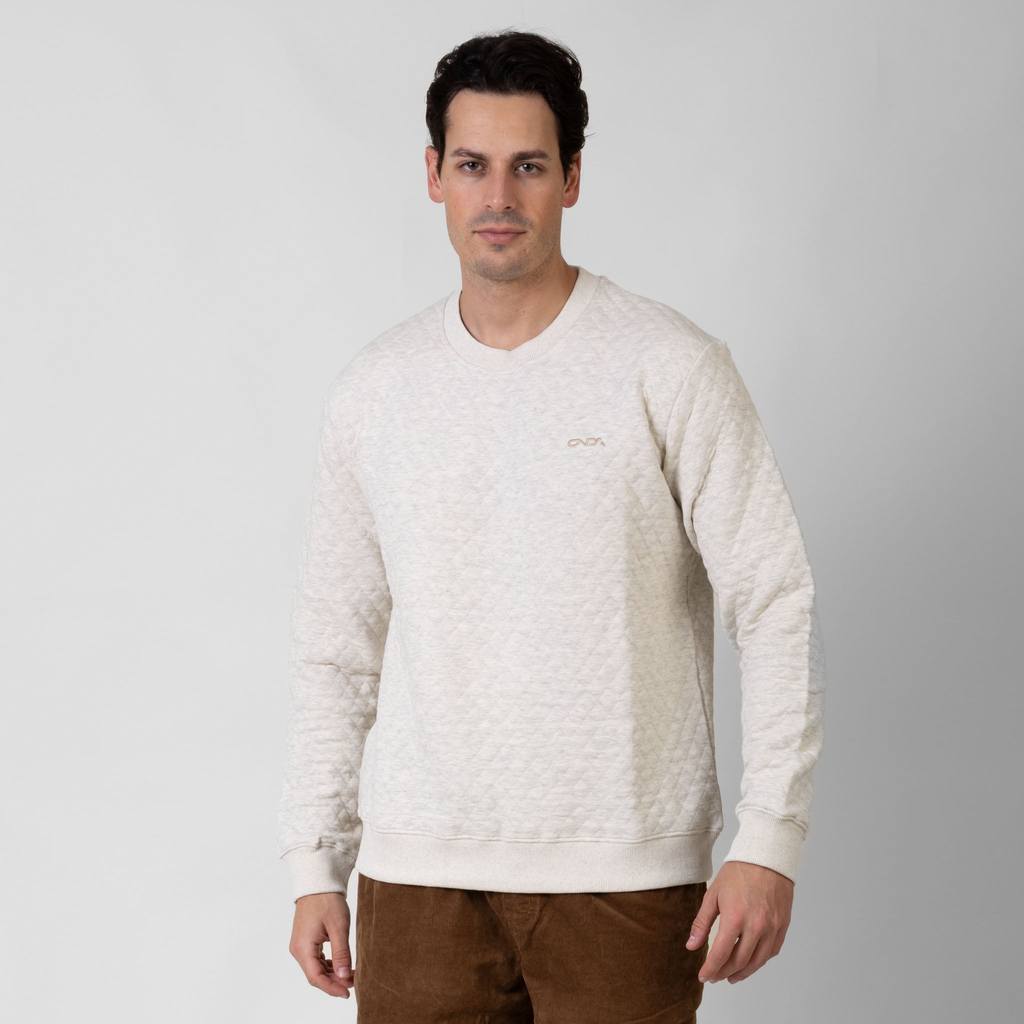 Man wearing a cream sweater against a white background