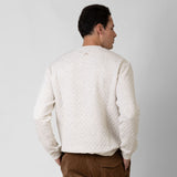 Man wearing a textured white sweater against a plain background